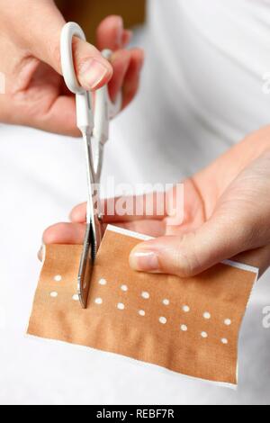 Bendaggio adesivo viene tagliato per trattare una piccola ferita Foto Stock