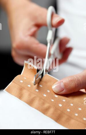 Bendaggio adesivo viene tagliato per trattare una piccola ferita Foto Stock