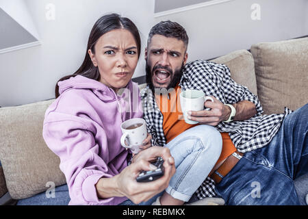 Emotional moody donna premendo un tasto sul telecomando Foto Stock