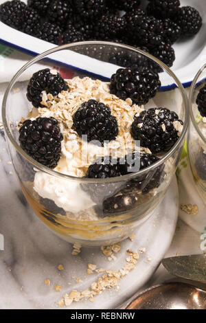 Cranachan, molto scottish dolce fatto con fiocchi di avena, more, il whisky e la panna montata in un bicchiere Foto Stock