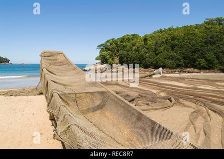Piccola barca da pesca e rete da pesca sulla spiaggia, Quilombola vicino a Ubatuba, Sao Paulo, Brasile Foto Stock