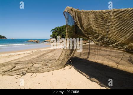 Piccola barca da pesca e rete da pesca sulla spiaggia, Quilombola vicino a Ubatuba, Sao Paulo, Brasile Foto Stock