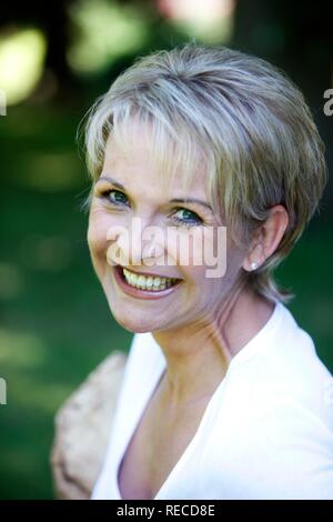 Ritratto di una donna, inizio 40s, nel giardino, guardando la telecamera, sorridente Foto Stock