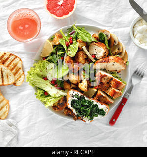 Ciotola di insalata fresca con bistecca di pollo e cavolfiore fritto su sfondo bianco con succo di pompelmo fresco vista superiore. Cibo sano concetto Foto Stock