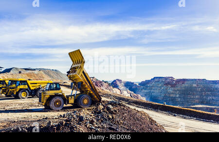 Autocarro con pianale di scarico inclinazione del carico di minerale nella miniera a cielo aperto di Riotinto con il cielo nuvoloso in background Foto Stock