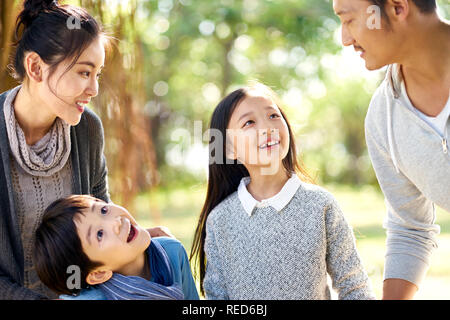 Famiglia asiatica con due bambini che si divertono ad esplorare i boschi in un parco. Foto Stock