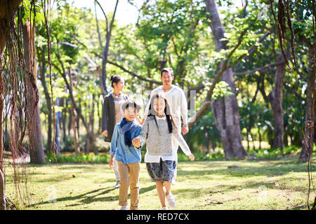 Famiglia asiatica con due bambini passeggiate rilassanti divertirsi nel parco felice e sorridente. Foto Stock
