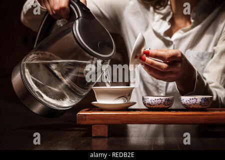 Ritagliato colpo di donna preparazione del tè in cinese tradizionale teaware. Foto Stock