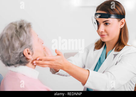 Medico palpating linfonodi di età paziente, esame medico a doctor office Foto Stock