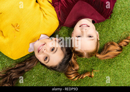 Vista dall'alto di sorridere studentesse che giace un testa a testa su un prato Foto Stock