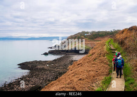 Gli escursionisti escursionismo su una passerella lungo l'isola di Anglesey sentiero costiero vicino a Benllech, Isola di Anglesey, Galles, Regno Unito, Gran Bretagna. Foto Stock