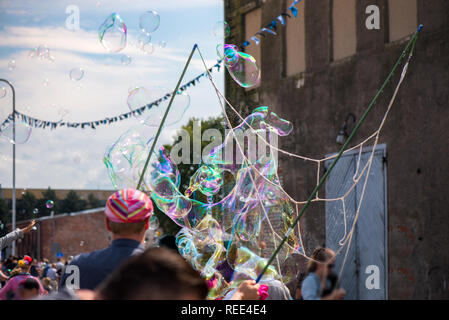 Un clown freelance soffiando centinaia di minuscoli, piccole e grandi bolle a festival all'aperto nel centro citta'. Concetto di intrattenimento, compleanni. I bambini aventi Foto Stock