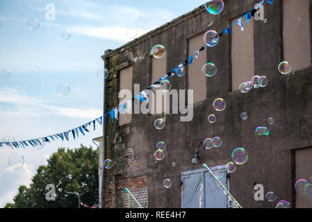 Un clown freelance soffiando centinaia di minuscoli, piccole e grandi bolle a festival all'aperto nel centro citta'. Concetto di intrattenimento, compleanni. I bambini aventi Foto Stock