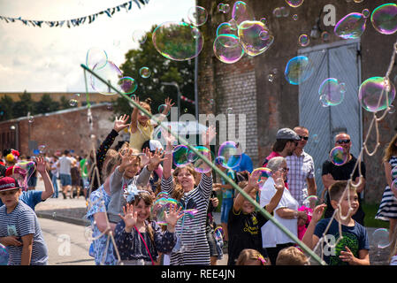 Un clown freelance soffiando centinaia di minuscoli, piccole e grandi bolle a festival all'aperto nel centro citta'. Concetto di intrattenimento, compleanni. I bambini aventi Foto Stock