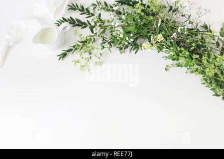 Nozze festosa, compleanno tabella scena con parvifolia eucalipto, nastro di seta, selvaggia prateria fiori e latte caraffa del bianco su sfondo tabella. Rustico Foto Stock