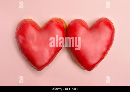 Valentino a forma di cuore le ciambelle rosso su sfondo rosa Foto Stock