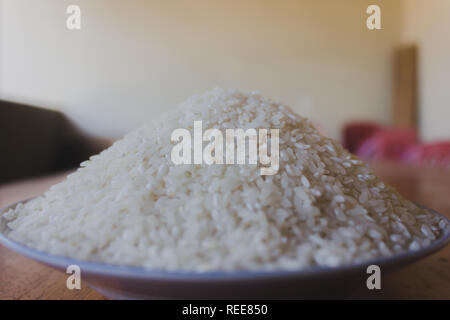 Bianco lucido del riso nella piastra su un tavolo di legno con sfocatura sullo sfondo Foto Stock