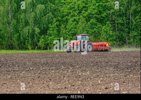 Verhovina, Russia - 30 Giugno 2017: Contadino con il trattore la semina - semina in campi agricoli Foto Stock