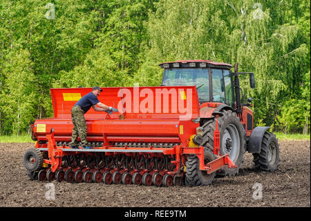 Verhovina, Russia - 30 Giugno 2017: Contadino con il trattore la semina - semina in campi agricoli Foto Stock