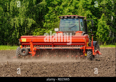 Verhovina, Russia - 30 Giugno 2017: Contadino con il trattore la semina - semina in campi agricoli Foto Stock