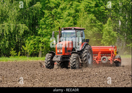 Verhovina, Russia - 30 Giugno 2017: Contadino con il trattore la semina - semina in campi agricoli Foto Stock