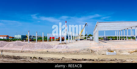 Panorama ripreso con grandangolo, gru mobile è operativo e di sollevamento di un travetto in cemento in cantiere. Foto Stock