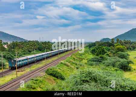 Vista spettacolare della ferrovia indiana che corre in pista va all'orizzonte in un paesaggio verde sotto il cielo blu con le nuvole. Foto Stock