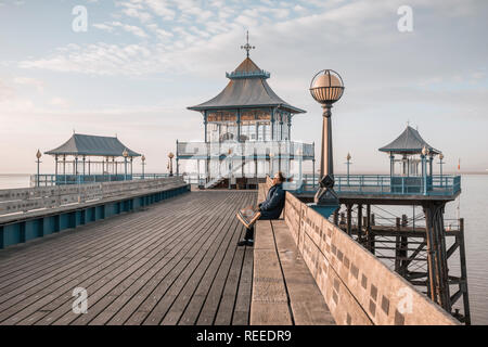 Donna seduta al sole, Clevedon Pier, vicino a Bristol, Inghilterra, Regno Unito Foto Stock