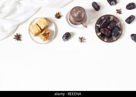 Il Ramadan Kareem bigliettino, invito. Piastra in bronzo con date di frutta, baklava pasticceria, tazza di caffè, anice stelle sul tavolo bianco. Iftar cena. Eid ul Foto Stock