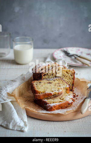 Fette di torta su un vassoio di legno e un bicchiere di latte su sfondo scuro Foto Stock