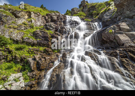 Capra cascata situata sulla famosa strada di Transfagarasan in Romania su un giorno di estate con una lunga esposizione. Foto Stock