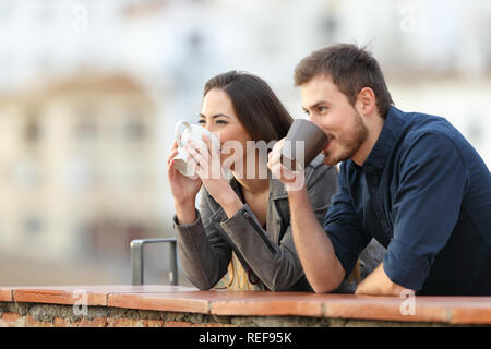 Coppia felice di bere il caffè contemplare viste all'aperto in una città in periferia Foto Stock