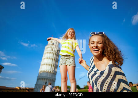 Moderno sorridente madre e figlia in posa per foto turistiche contro la torre pendente di Pisa, Italia. prendendo silly fotografie è un must qui. avente mi Foto Stock