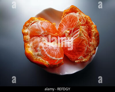 Rotto il mandarino, tangerine peel. Succose fette di arancio mandarino sono sulla buccia. Ancora Vita con Mandarin Foto Stock