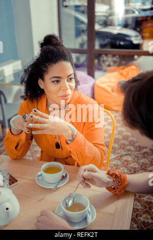 Ragazza condividendo una storia interessante con il suo amico Foto Stock