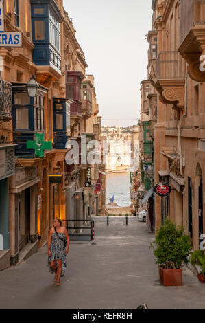 Una vista verso il basso San Gwann Street (Triq San Gwann). Si tratta di una tipica stradina secondaria di negozi e residenze nel centro di La Valletta, la capitale di murata di M Foto Stock