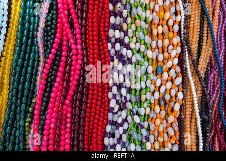 Sfondo colorato e Collana fatta di pietre preziose e di perle colorate esposte in un negozio. Semi preziosi gioielli. Foto Stock