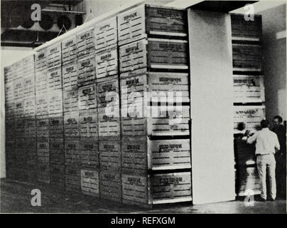 . Raffreddamento commerciale di frutta e verdura. Frutta; frutta; verdure. Fig. 22. A circolazione forzata di aria di raffreddamento nei contenitori prima di imballaggio. Il plenum centrale qui è bloccato con il legno compensato pan- els che coprono la parte superiore e posteriore aperture della pila. Aria è così costretto a passare attraverso il contenitore di sfiati laterali e intorno a produrre per raggiungere i ventilatori di scarico. Le soffianti devono essere arrestato quando il raffreddamento è completato. Ogni stazione di questa installazione è in grado di effettuare il raffreddamento 60 tonnellate di produrre. spazio necessario per produrre essendo raffreddata per un dato tasso di produrre manipolati, ma aumenta il costo di circolazione di aria e può richiedere un Foto Stock