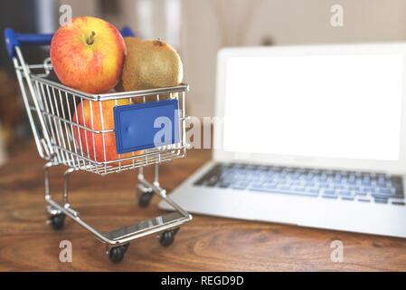 Miniatura shopping card con frutta fresca e il portatile sul tavolo Foto Stock