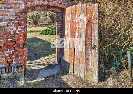 Vista in dettaglio di un muro di mattoni con una vecchia porta di legno Foto Stock