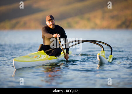 Ritratto di un uomo sorridente pagaiando in kayak sulle rive di un fiume. Foto Stock