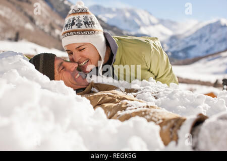 Ridere metà donna adulta accanto a suo marito che giace sepolto nella neve. Foto Stock