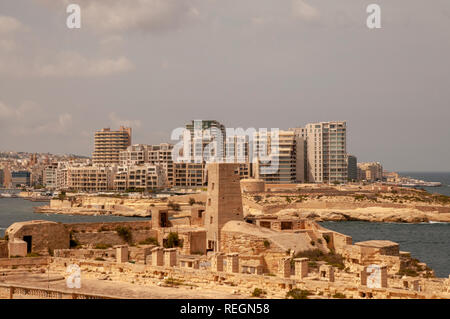 Edificio alto e moderno di edifici in Sliema seduta tutta la retta da La Valletta, Malta, con parte di Fort St Elmo in primo piano. Foto Stock