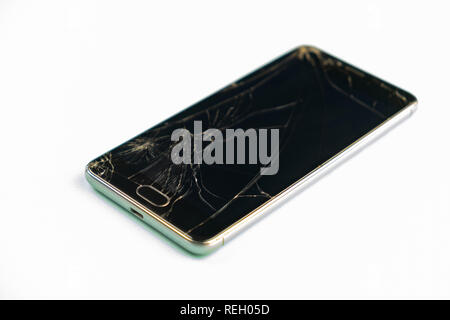 Telefono cellulare con rotture di schermo nero, vista dall'alto. Addolorato danneggiato lo smartphone nel verde pallido sfondo, profondità di campo Foto Stock