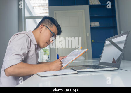 Vista laterale della sede asiatica uomo la scrittura della nota Foto Stock
