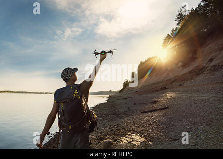 Maschio di lancio turistico drone di mano nel bel tramonto nel bosco. Foto Stock