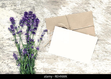 Branding elegante mockup per visualizzare le tue opere. biglietto di auguri e Lavanda fiori bianchi su sfondo di legno. Appartamento laici vista superiore Foto Stock