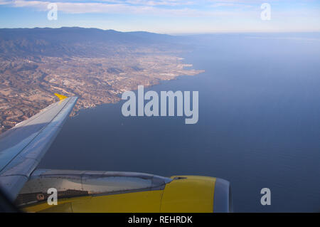 Vista panoramica della costa dall'interno di un aereo commerciale da cui parte del parafango e il suo motore di sinistra può essere visto Foto Stock