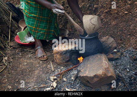 Una donna di preparare un pasto di sorgo su un fuoco aperto, Uganda Foto Stock