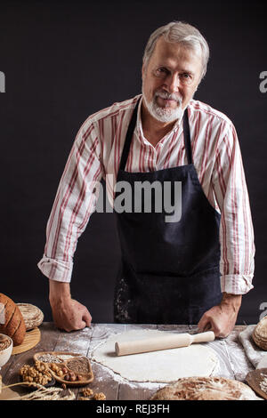 Sperimentato Baker uomo preparazione impasto per il pane fatto in casa in cucina. Foto Stock